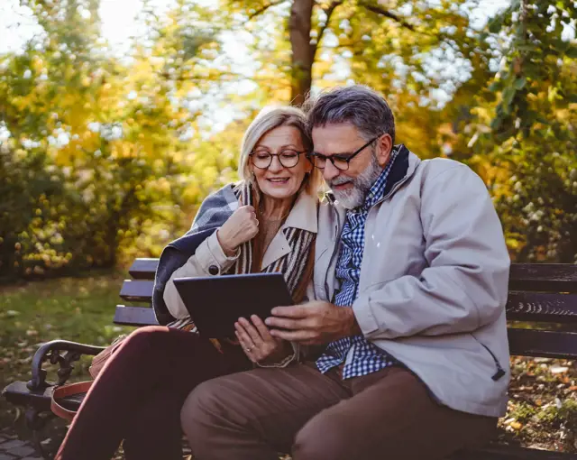couple de personnes senior heureux assis sur un banc en automne