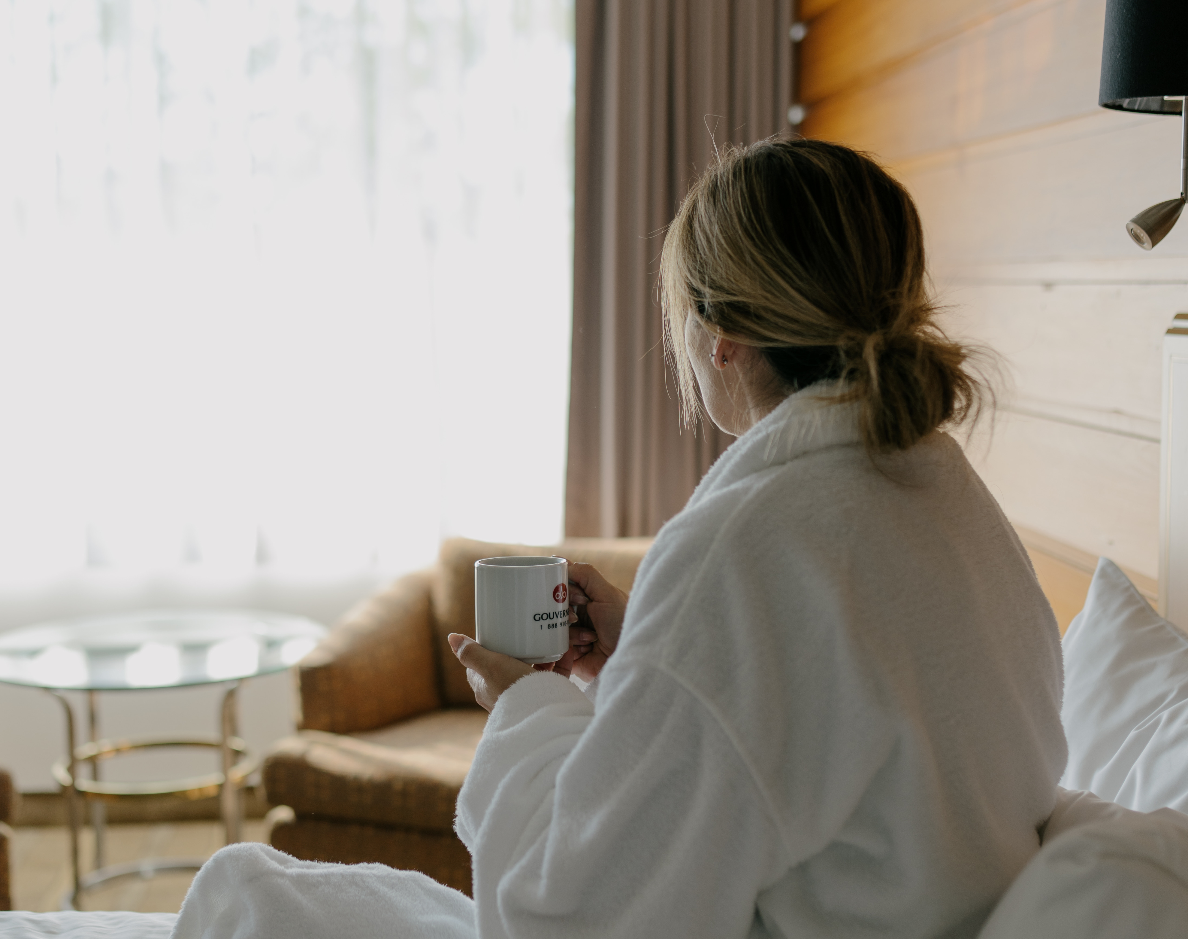 Hotels Gouverneur Femme de dos sur le lit avec café à la main